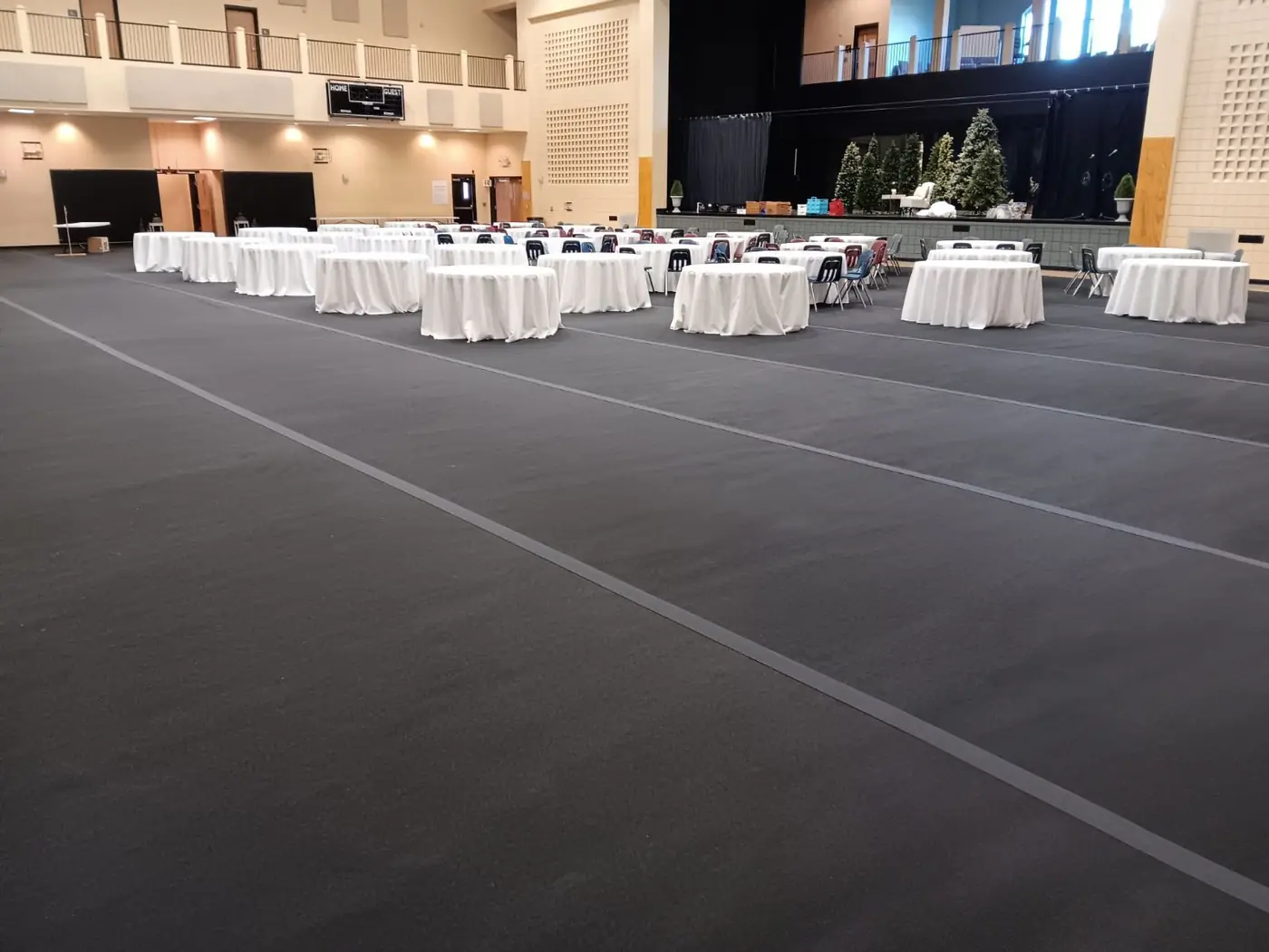 Round tables set on floor-protection rolls in a school gym